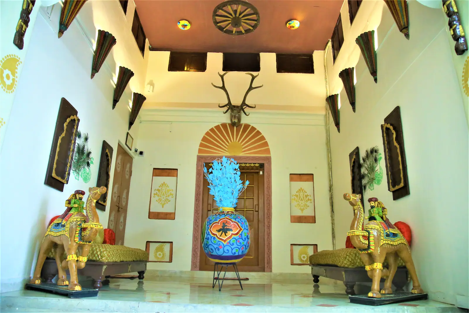 Haveli lobby with carved wooden door, painted camel statues and traditional artwork