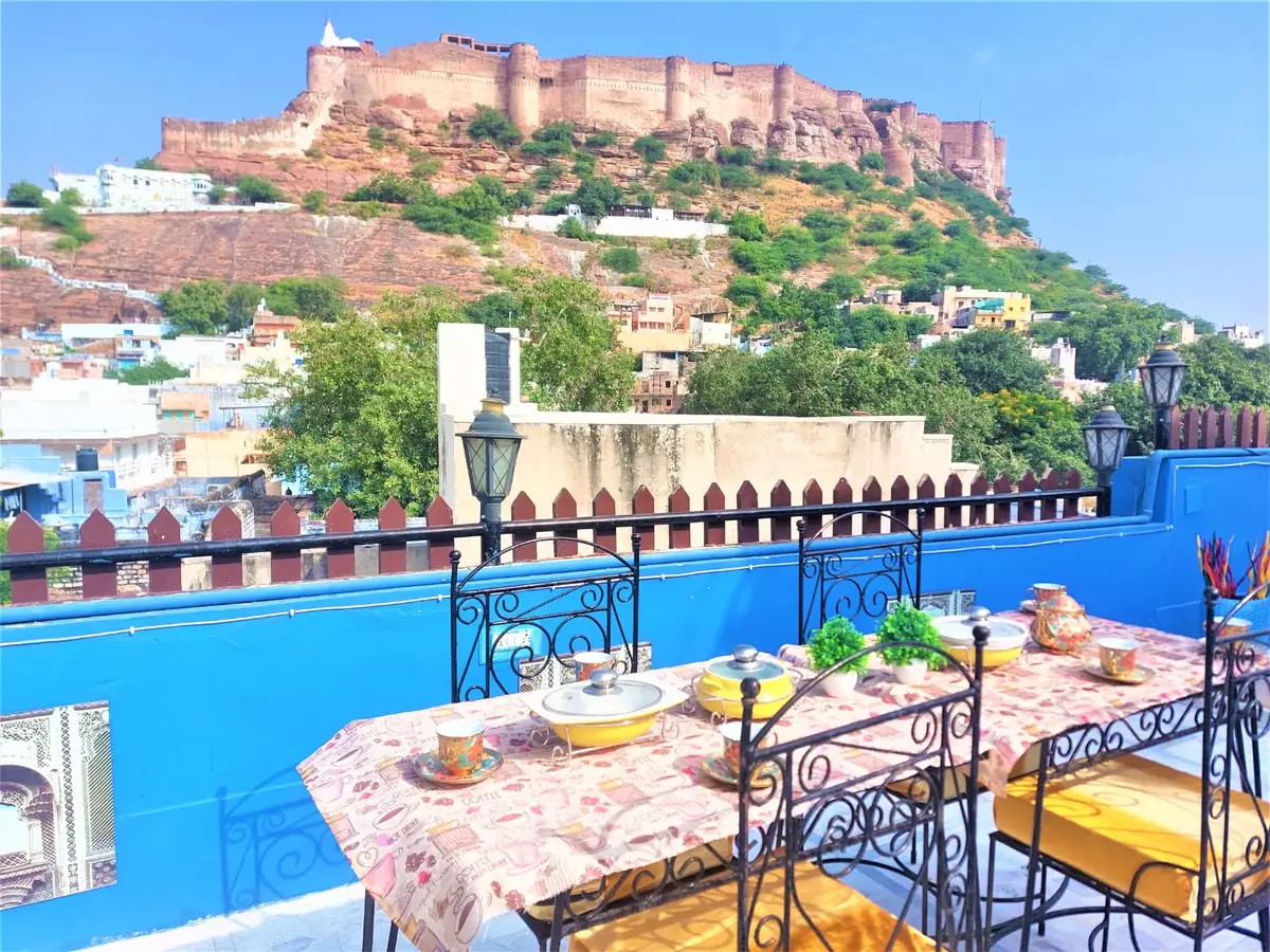 Breakfast table set on the haveli rooftop terrace with the blue city of Jodhpur and Mehrangarh Fort in the background