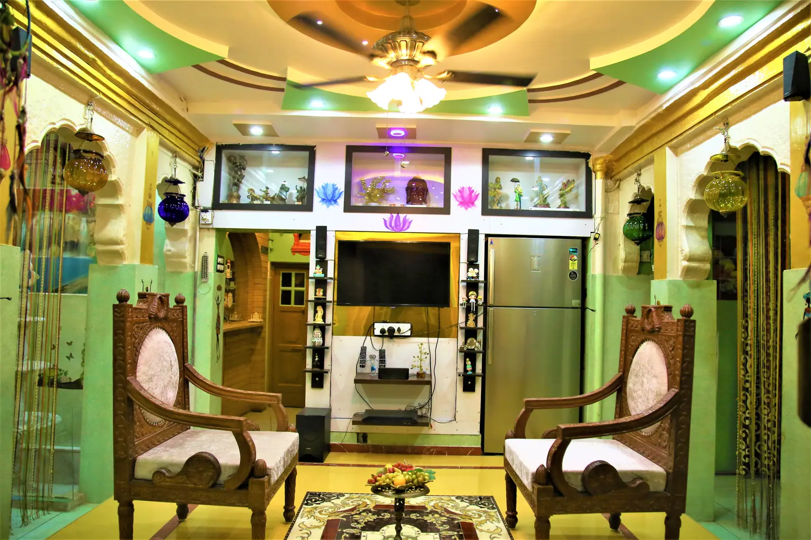 Guest lounge with carved chairs, refrigerator and television in the heritage haveli