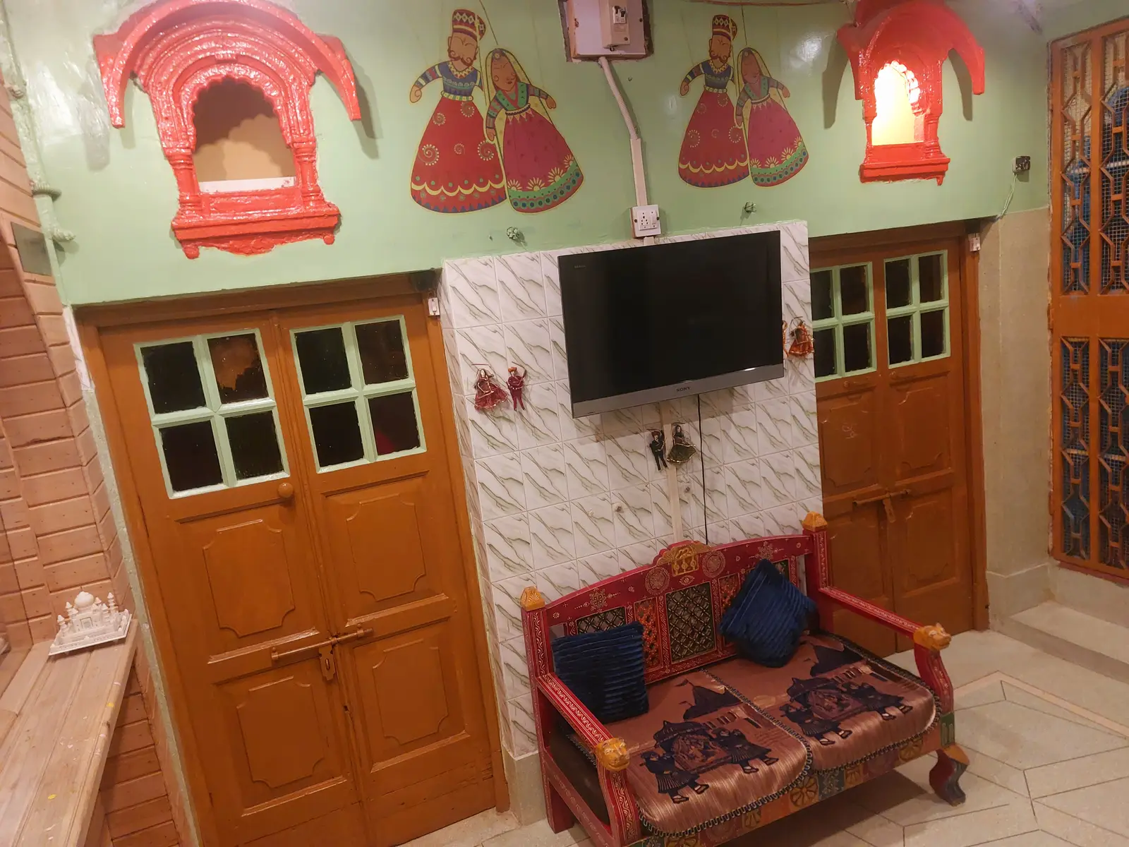 Rajasthani puppet artwork, LED television and carved wooden seating in the Palatial Deluxe Room